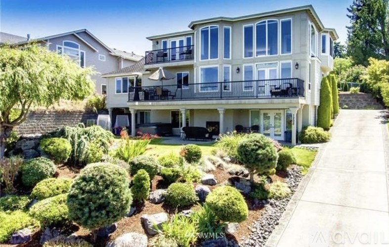 A large, two-story house with a balcony and a well-maintained garden.