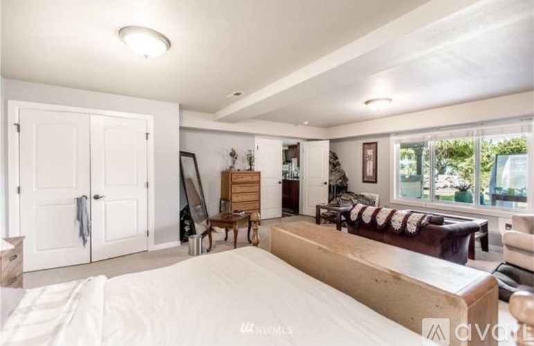 A bedroom with a large bed and a window with a view of trees.