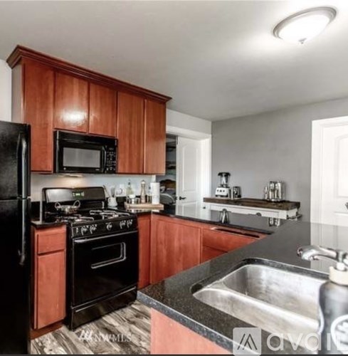 A kitchen with black appliances and wooden cabinets.