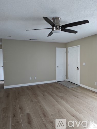 A room with a ceiling fan and wooden flooring.