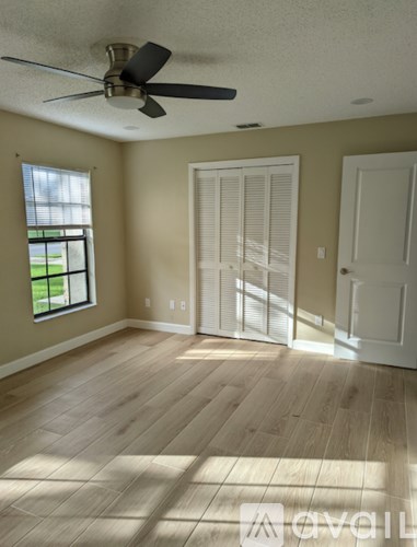 A room with a ceiling fan and wooden flooring.