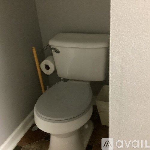 A white toilet with a roll of toilet paper on top of it.