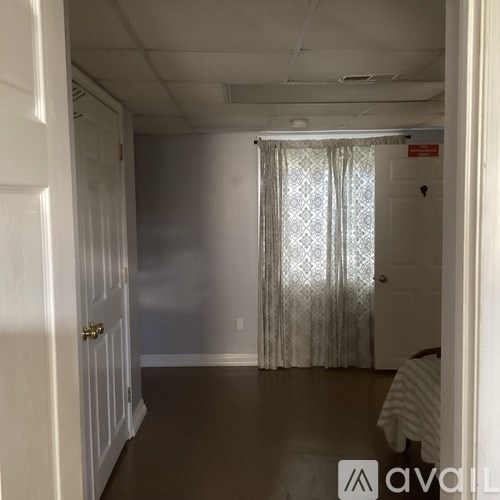 A room with a door, a window with curtains, and a bed with a striped blanket.