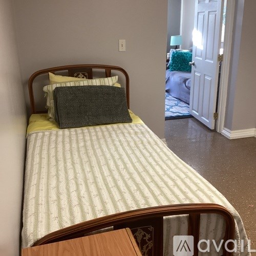 A bed with a green pillow and a striped comforter is in the foreground of the image.