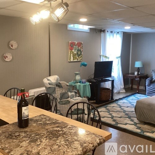 A room with a table, chairs, and a bottle of wine.