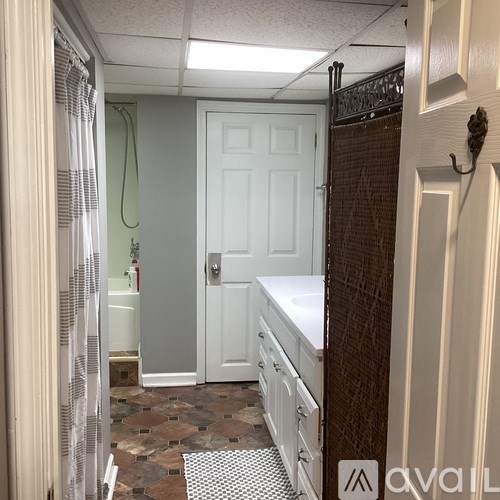 A bathroom with a white door and a brown tiled floor.