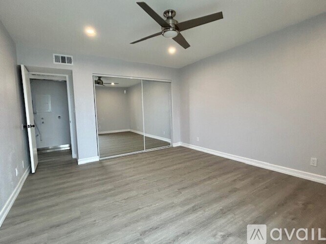 A spacious room with a ceiling fan and wooden flooring.