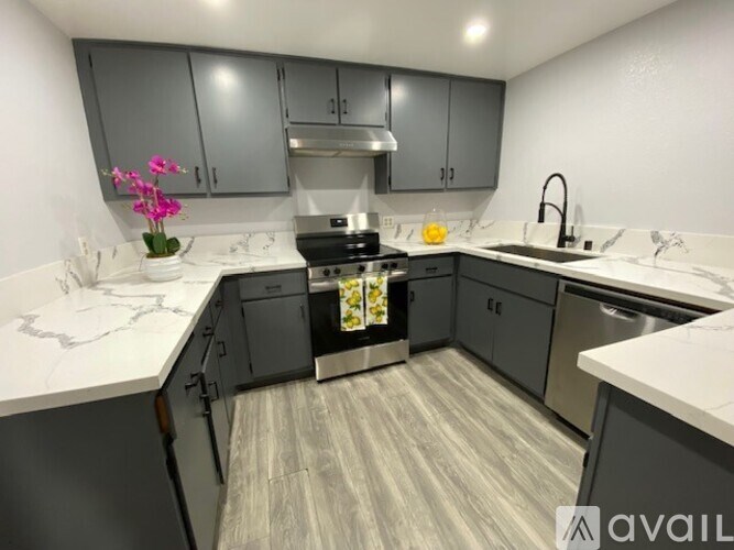 A kitchen with grey cabinets and a white countertop.