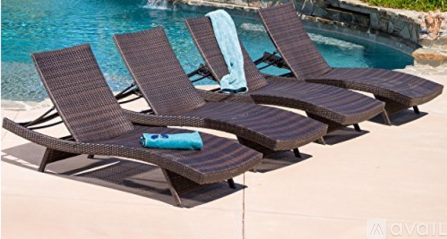 A set of four brown lounge chairs with blue towels on them.