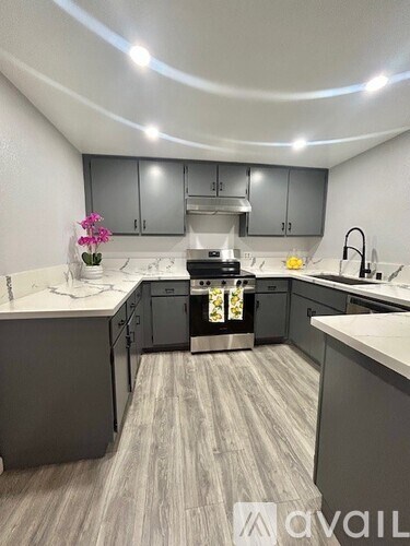 A kitchen with a white countertop and grey cabinets.
