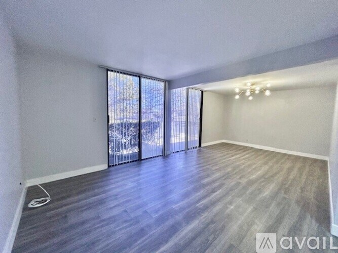 A spacious room with wooden flooring and sliding glass doors.