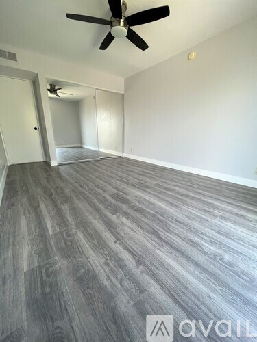 A room with a ceiling fan and wooden flooring.