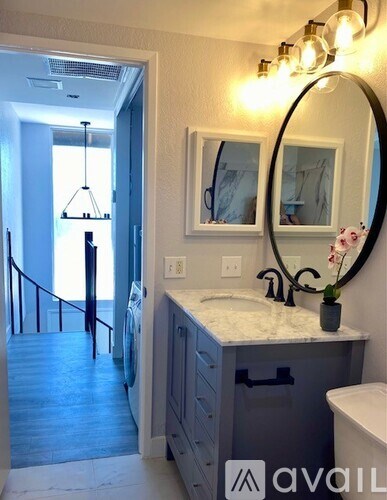 A bathroom with a sink, mirror, and a view of a hallway.