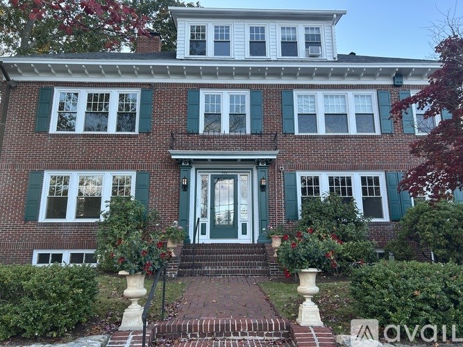 A red brick house with green shutters and a white door.