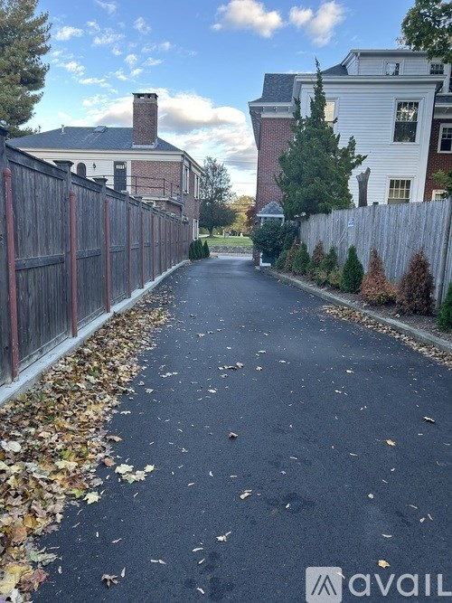 A residential street with houses on both sides and a fence on the left.