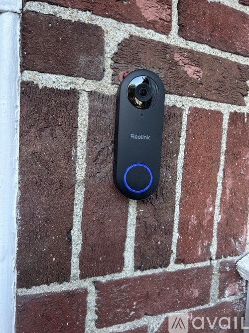 A Reolink security camera is mounted on a brick wall.