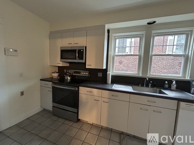 A kitchen with white cabinets and black countertops.