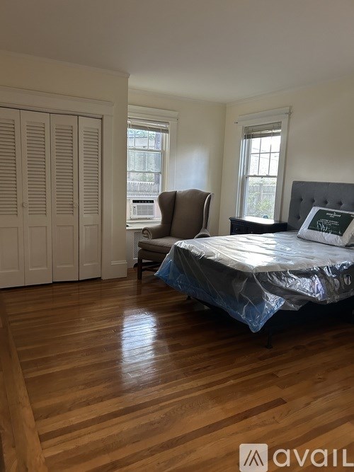 A bedroom with a bed covered in plastic and a chair in the corner.