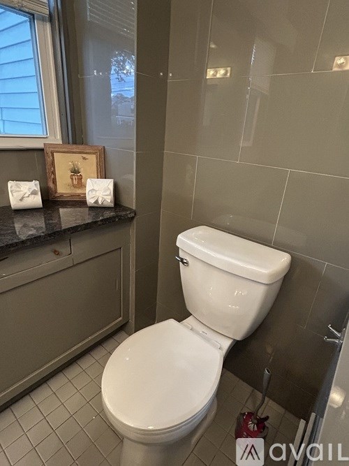 A white toilet in a bathroom with a tiled floor and grey walls.
