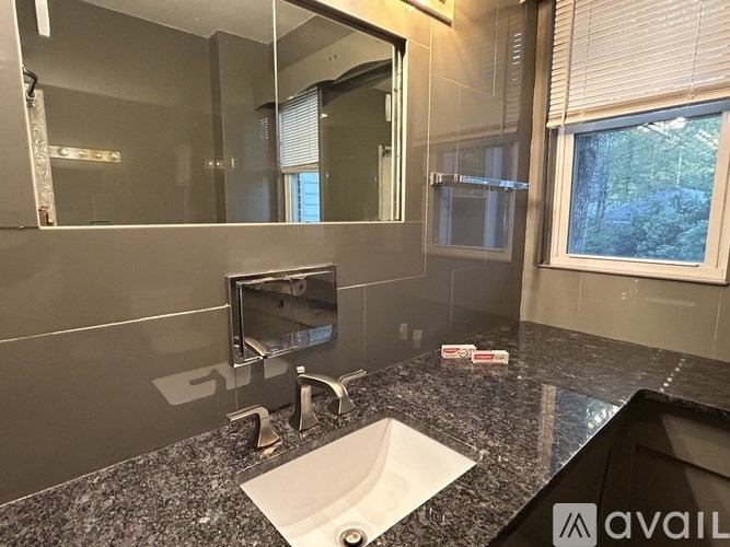 A bathroom with a sink, mirror, and window.