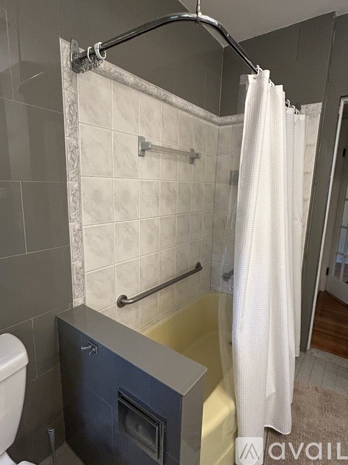 A bathroom with a white shower curtain and a black tub.