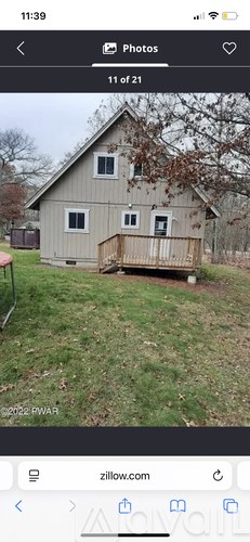 A small house with a porch is surrounded by a grassy area.