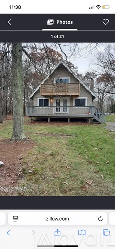 A house with a porch and a tree in front of it.