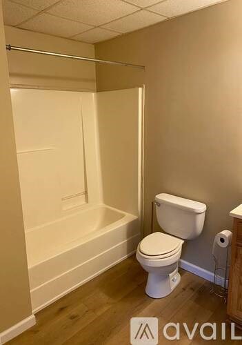 A white toilet sits in a bathroom with a walk-in shower.