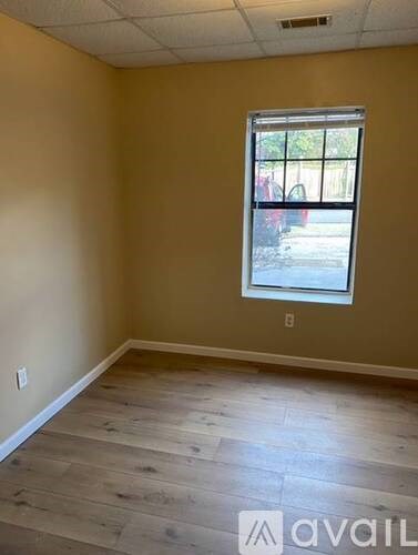 A room with a window and wooden flooring.