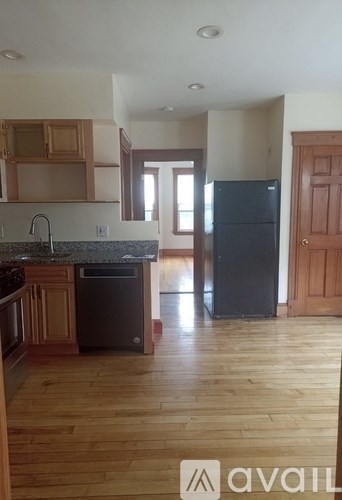 A kitchen with wooden floors and a black fridge.