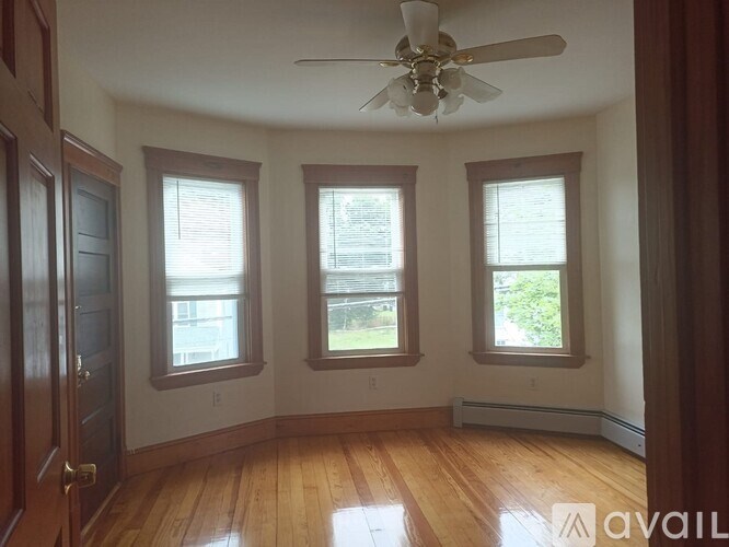 A room with wooden floors and three windows.