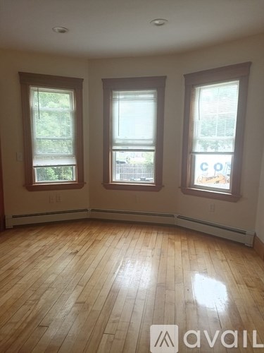 A room with wooden floors and three windows.