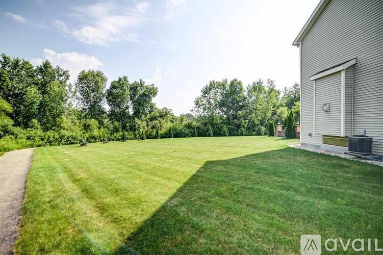 A grassy field with a building and trees in the background.
