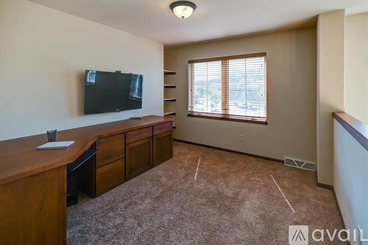 A room with a brown carpet and a wooden desk with drawers.