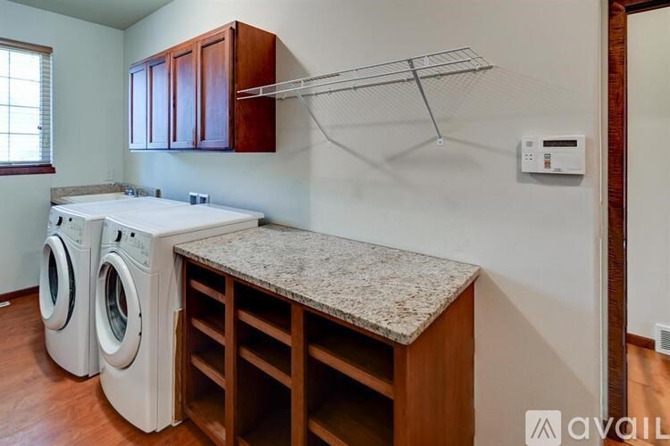 A laundry room with a washer and dryer, a countertop, and wooden cabinets.