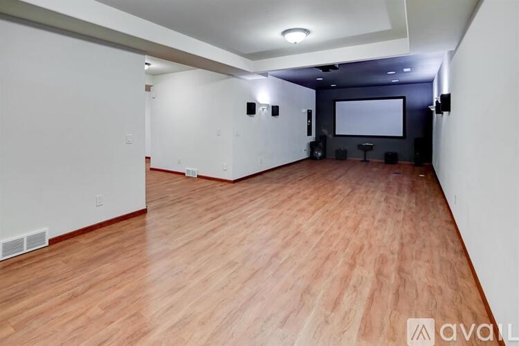 A spacious room with wooden flooring and a projection screen.