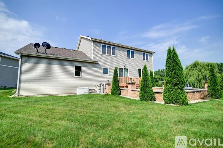 A house with a satellite dish on the roof is surrounded by greenery.