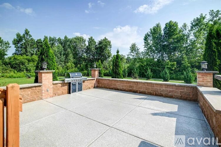A patio with a concrete floor and a brick wall with a chimney on top.