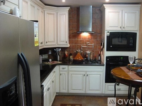 A kitchen with white cabinets and a black fridge.