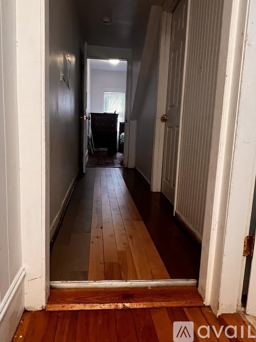 A long hallway with a wooden floor and white walls.