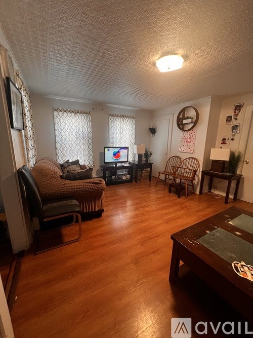 A living room with a wooden floor and a television on a stand.