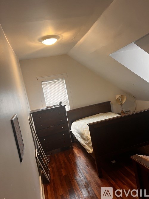 A bedroom with a bed, dresser, and window.