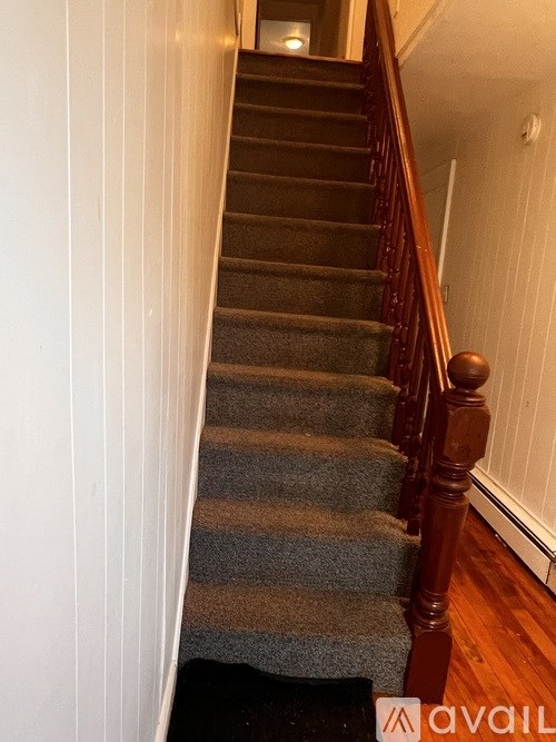 A staircase with a striped carpet and wooden balusters.