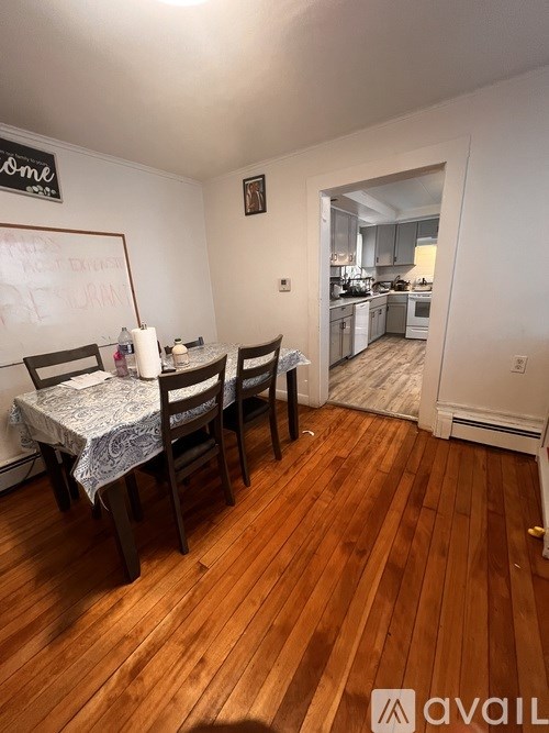 A dining room with a whiteboard and wooden floors.