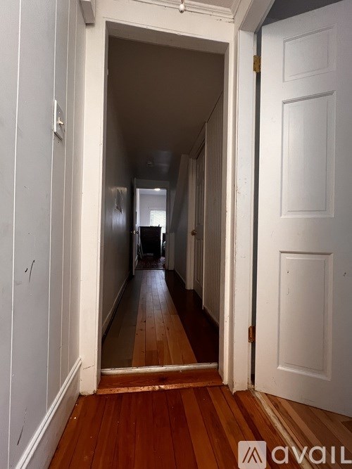 A hallway with a wooden floor and white walls.