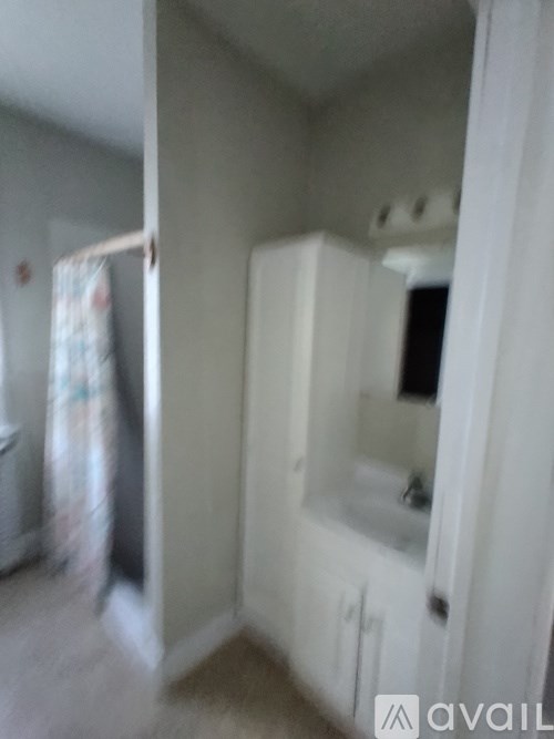 A bathroom with a white cabinet and a mirror.