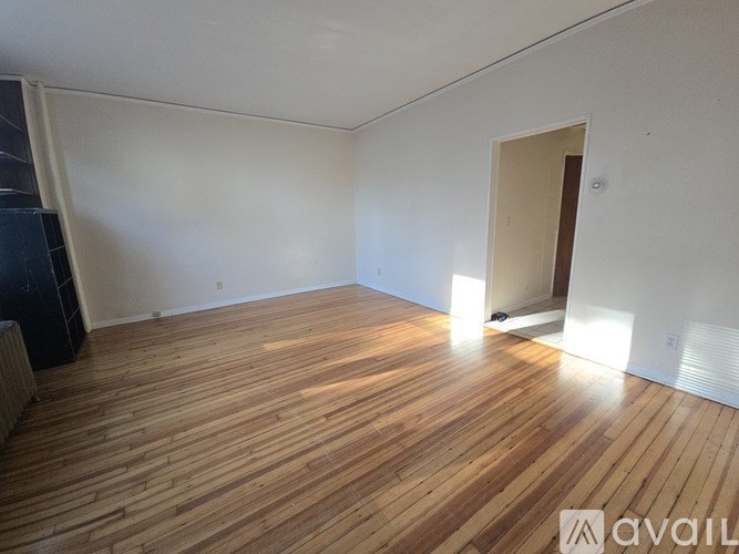 A room with wooden flooring and a doorway leading to another room.