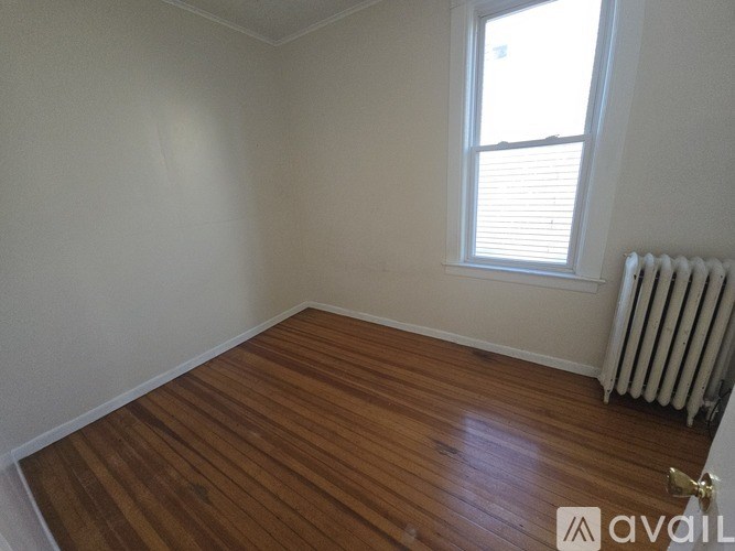 A room with wooden flooring and a window with blinds.
