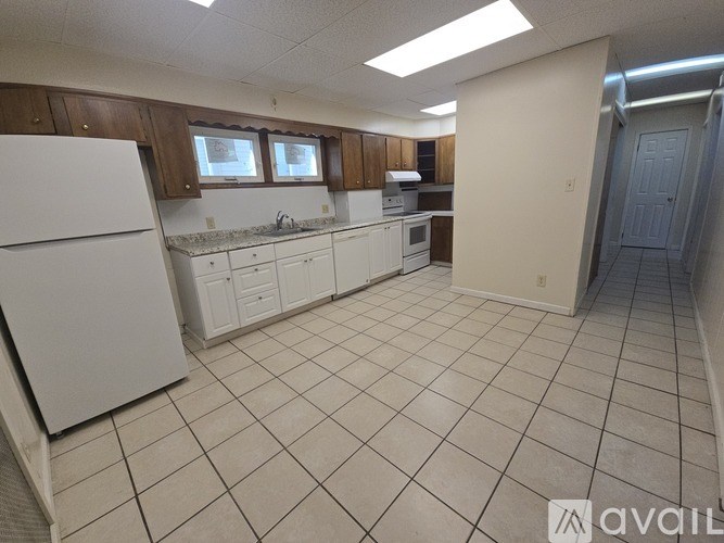 A kitchen with white appliances and brown cabinets.