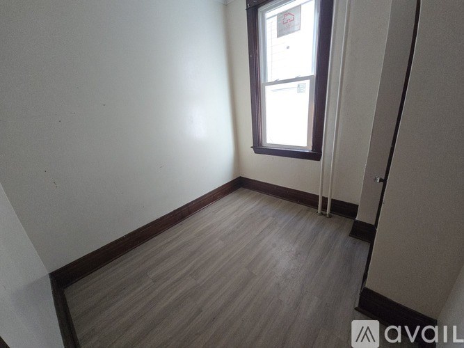 A room with a window and wooden flooring.